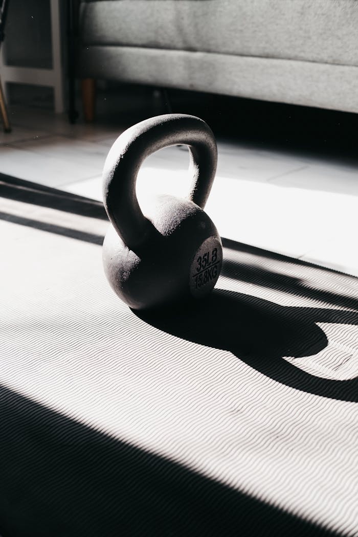 why-choose-us Kettlebell in bright sunlight casting shadow on gym mat indoors, perfect for fitness themes.
